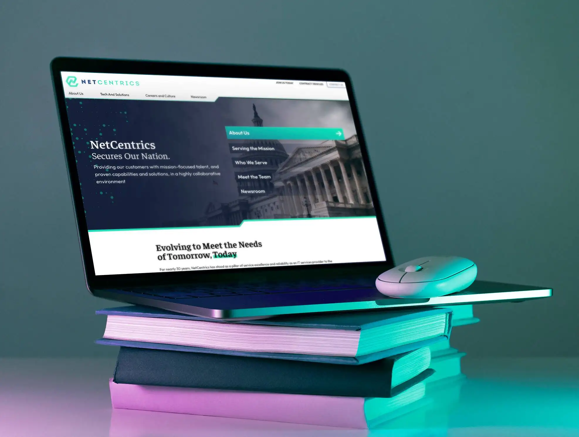 laptop sitting on books with website development work for net centrics client showing on screen